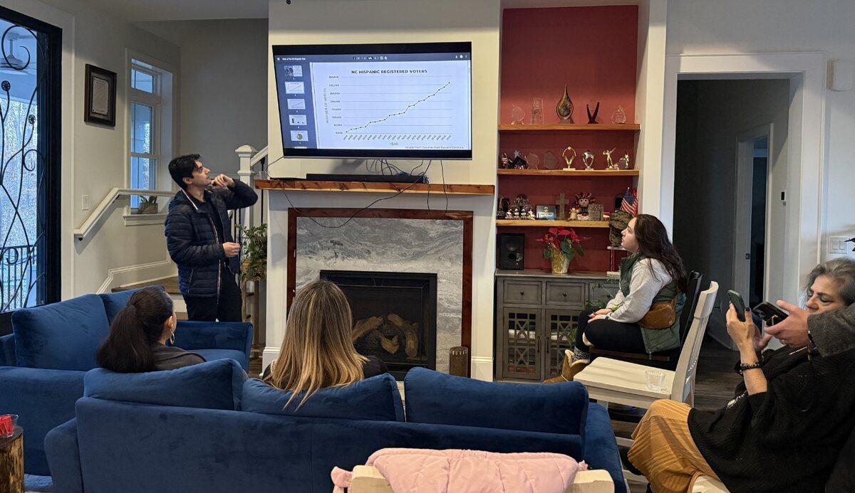 A Camino team member presenting NC Hispanic voter registration data to community members in a living room